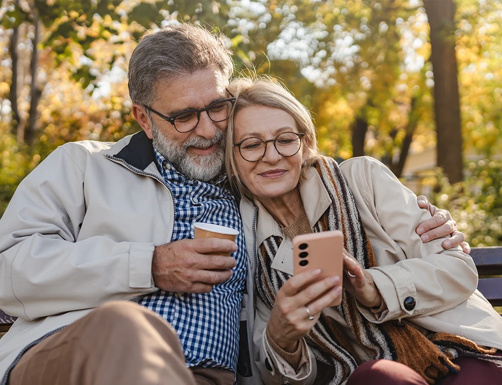 reifes Pärchen sitzt auf Bank und genießt entspannt den Tag, da sie sich nicht um die Solarfinanzierung sorgen müssen