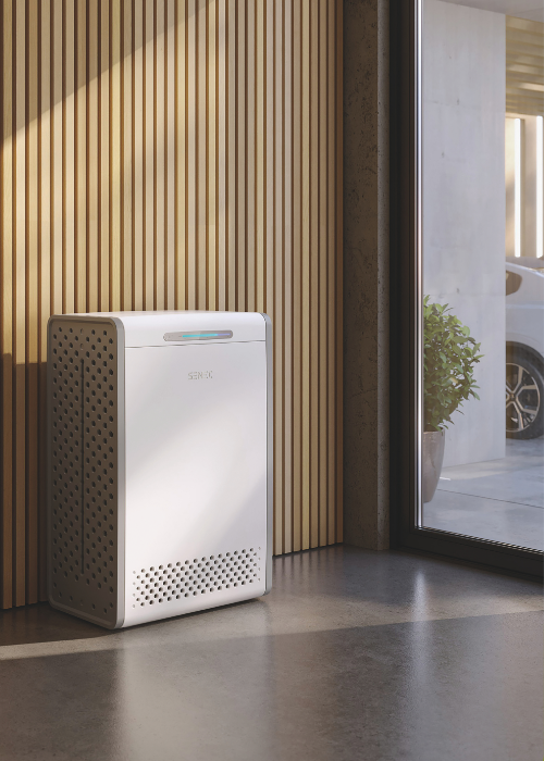 Moderner SENEC-Stromspeicher im Innenraum vor einer Holzlamellenwand, neben einem großen Fenster mit Blick auf eine Einfahrt und ein geparktes Auto.