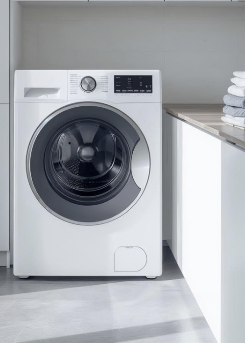 Moderne Frontlader-Waschmaschine in einer hellen Waschküche, daneben ein Stapel gefalteter Handtücher auf der Arbeitsfläche.