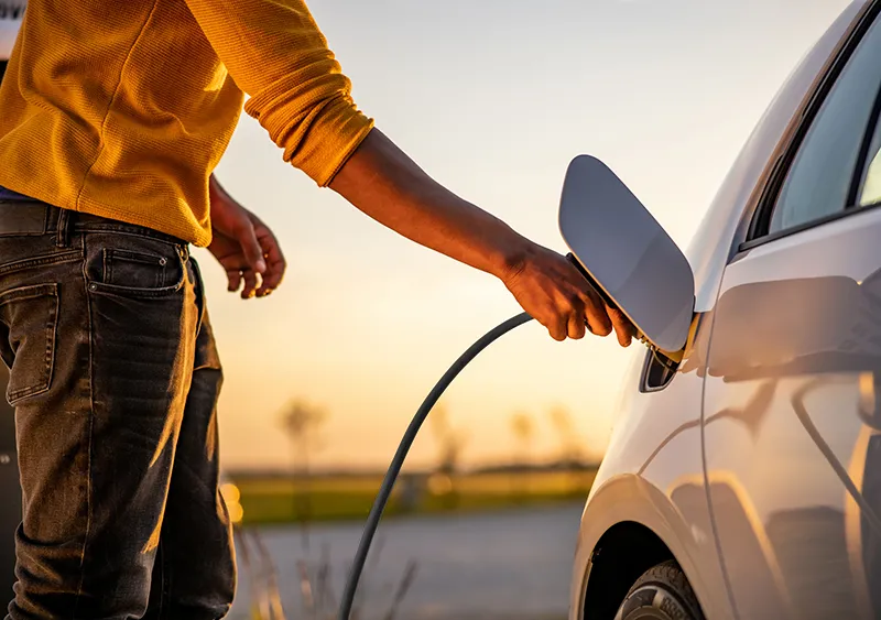 Das Bild zeigt eine Person beim Laden eines Elektroautos. Das Motiv eignet sich für Inhalte rund um Wallboxen, E-Mobilität, Ladeinfrastruktur und mögliche Förderprogramme.
