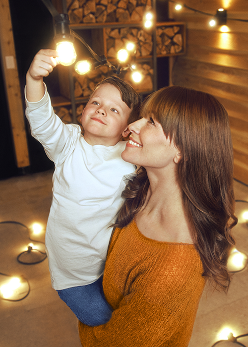 Mutter mit Kind, das an Glühbirne fässt vor SENEC Stromspeicher