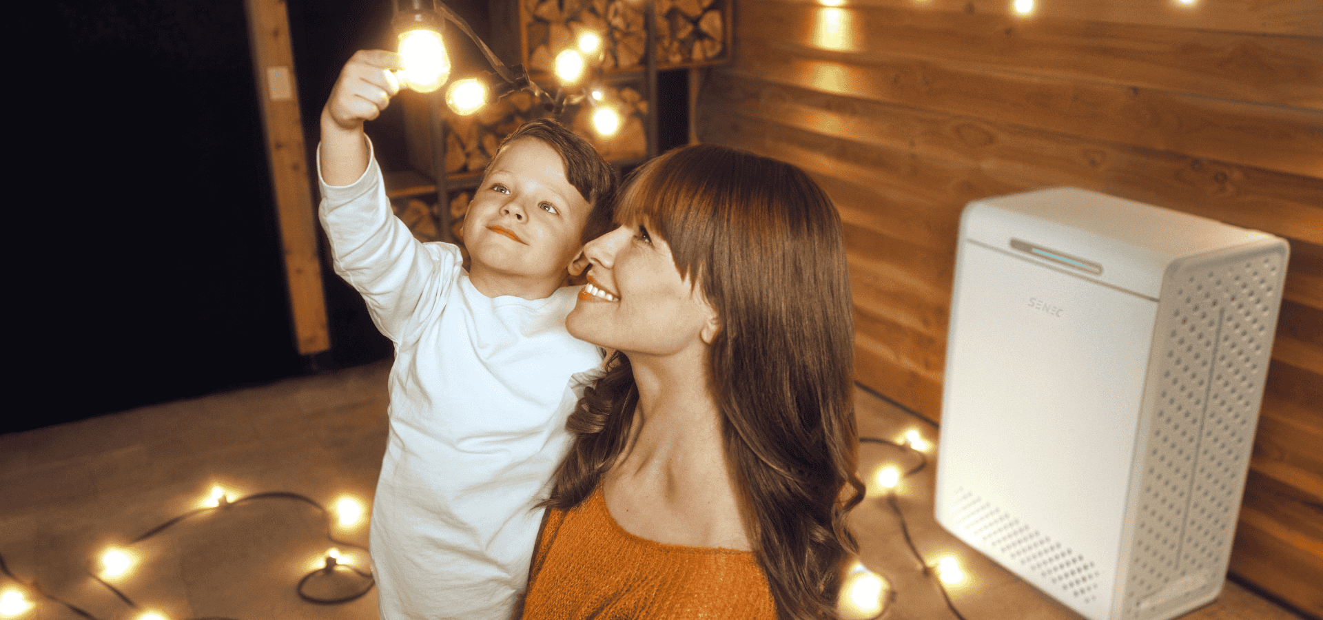 Mutter mit Kind, das an Glühbirne fässt vor SENEC Stromspeicher
