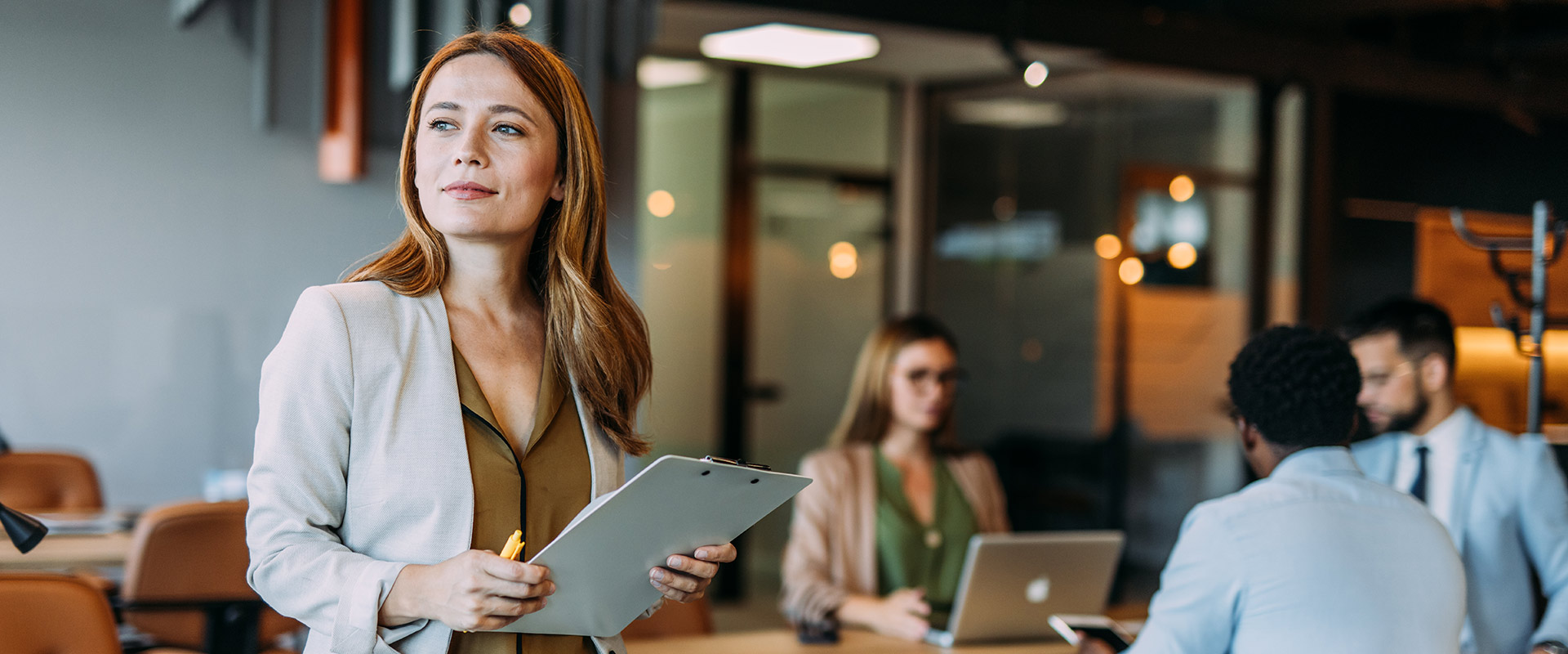 Unternehmerin steht im Büro und prüft Unterlagen zur Photovoltaikanschaffung.